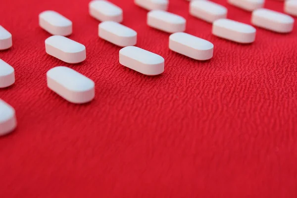 Medicine concept. White tablets are laid out in a line on a red background. Pill red frame isolated. Medicines or drugs arranged in a rectangular frame on light blue gradient background,medicine.
