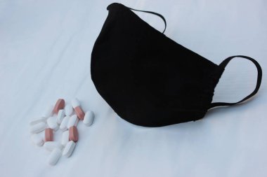 Siyah tıbbi yüz kalkanı ve beyaz arka planda haplı metinler için yer. Beyaz ve bej tabletli siyah yüz kalkanı beyaz üzerine izole. Solunum koruması. Gribe karşı korunmak için