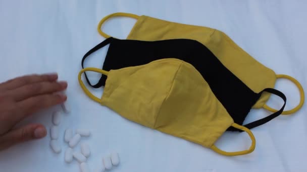 黑色和黄色的医疗面具和手记药丸 防止结肠炎的发生 一个女人在白色背景的医疗保护面具旁边数着白色药丸 后续行动 — 图库视频影像
