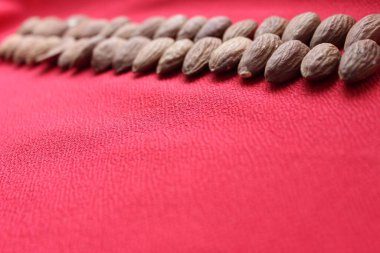 Kırmızı zemin üzerinde çizgi olan bademler. Bademler mesaj için yere yakın dururlar. Fındık ve kurutulmuş meyve, sağlıklı beslenme.