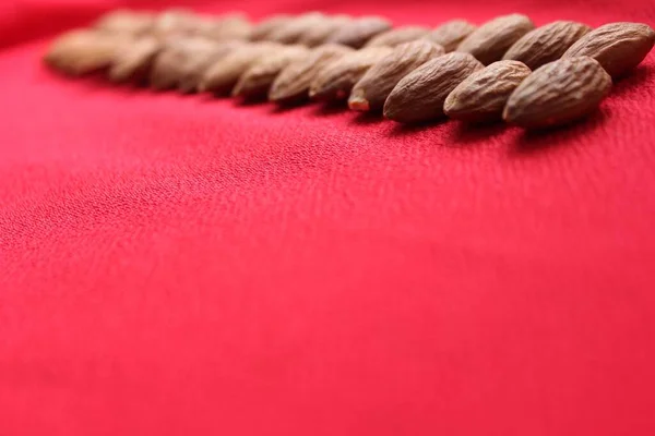 Almonds lined with a line on a red background. Almonds closeup with place for text. Nuts and dried fruits, healthy nutrition.