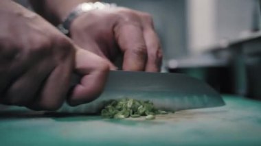 Şef keskin bir bıçakla yeşil soğan keser.