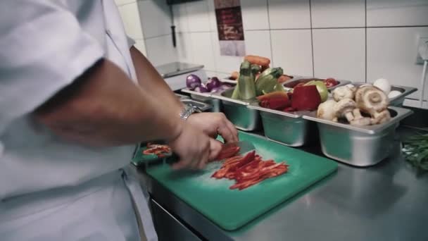 Chef snijdt paprika en doet in een witte container — Stockvideo