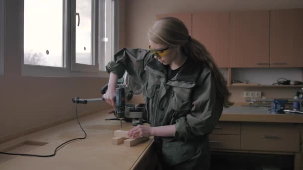 Mädchen schraubt eine Schraube in einen Holzrohling — Stockvideo