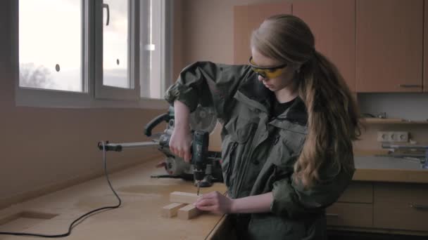 Chica gira un destornillador en un espacio en blanco de madera — Vídeos de Stock