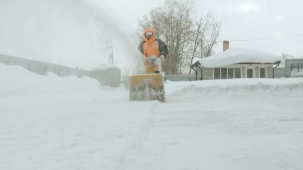 O homem limpa a neve com um lança-neves. Movimento na câmera — Vídeo de Stock