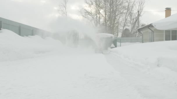 El hombre limpia la nieve con un lanzador de nieve — Vídeo de stock