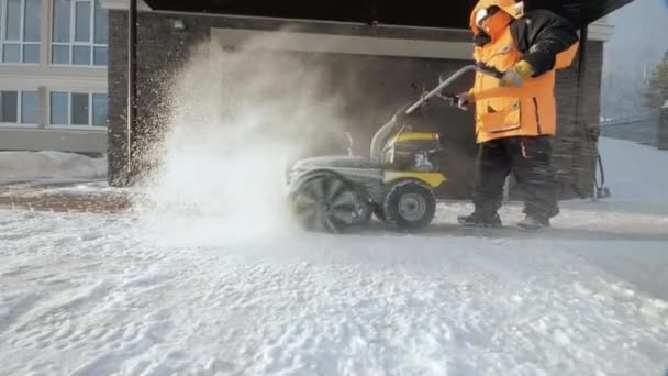 L'homme nettoie la neige dans la cour avec une balayeuse en hiver — Video