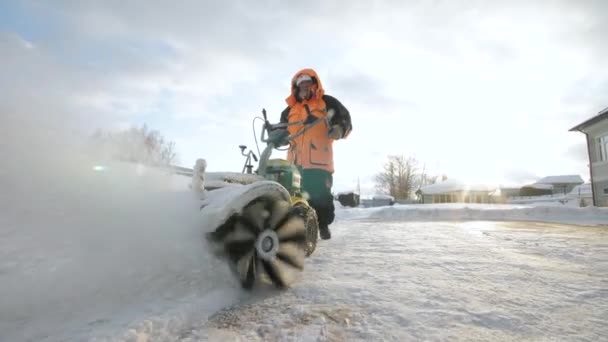 El hombre limpia la nieve en el patio con una barredora en el invierno — Vídeos de Stock