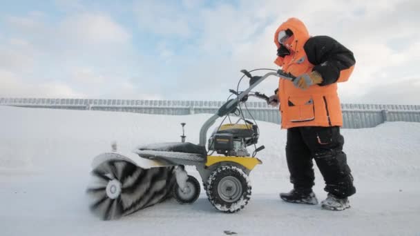 Man cleans snow in the yard with a sweeper in the winter — Stock Video