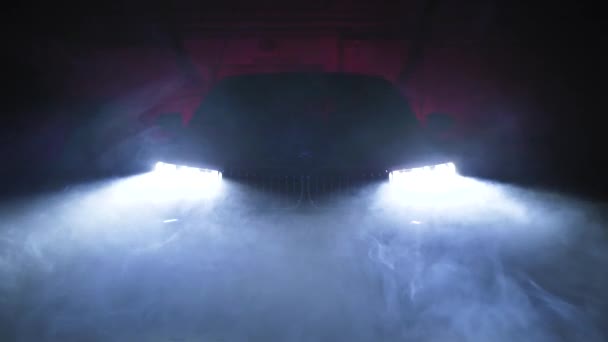 TOMSK, RUSIA - 26 de julio de 2019: BMW 7 Series optics view through smoke, black background. Iluminación de color. Adaptador led — Vídeos de Stock