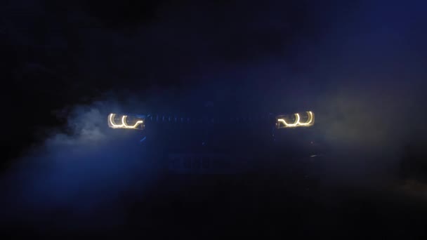 TOMSK, RUSIA - 26 de julio de 2019: BMW 7 Series optics view through smoke, black background. Iluminación de color. Adaptador led — Vídeo de stock