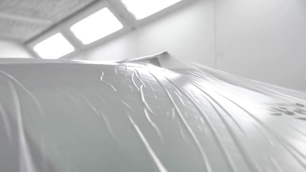 Bílé auto stojí ve stříkací kabině pokryté průhlednou fólií. Připraveno k malování — Stock video