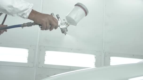 Proces malování bílého auta ve stříkací kabině. Muž se stříkací pistolí — Stock video