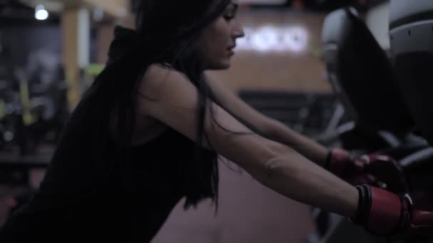 Atletisch sexy meisje verslaat een bokszak, sportschool workout, t-shirt met een kap — Stockvideo
