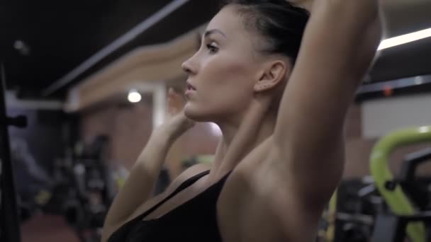 Athletic sexy girl in gym collects hair in a bun so as not to interfere — Stock Video