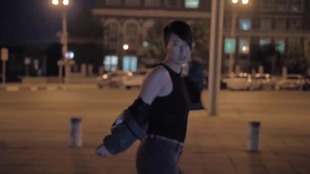 非常にスタイリッシュなアジアの女の子は夜に街の通りで踊ります。印象的な韓国の女の子 — ストック動画