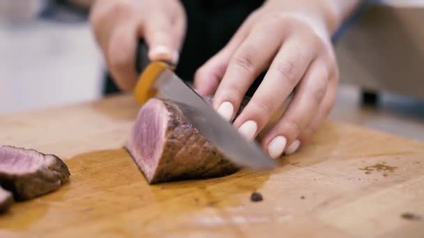 Meisje chef snijdt vlees steak in plakjes — Stockvideo