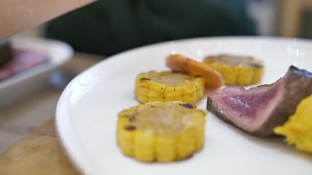 Beyaz bir tabakta biftek ve mısır püresi. — Stok video