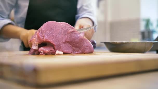 Chef menina corta um grande pedaço de carne fresca na cozinha — Vídeo de Stock