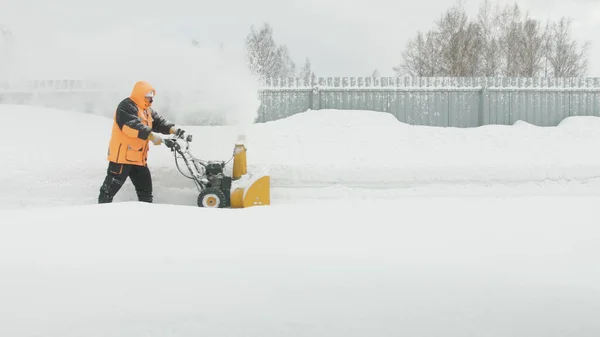 Man cleans snow with a snow thrower goes left to right