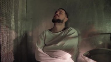 Psikiyatri hastanesinde deli gömleği giymiş deli bir adam.