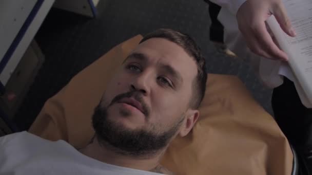 Psycho leží na gauči v sanitce, doktor se snaží zjistit příčinu jeho nemoci — Stock video
