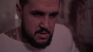 Deli gömleği giymiş deli bir adam sandalyeye bağlanmış, kanlı duvarlı bir odada katil bir psikopat.