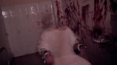 Deli gömleği giymiş deli bir adam sandalyeye bağlanmış, duvarları kanlı bir odada katil bir psikopat, aşırı doz, ölüm.