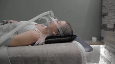 Girl lies on bed with artificial respiration mask