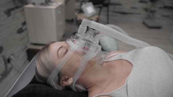 Girl lies on bed with artificial respiration mask — Stockvideo