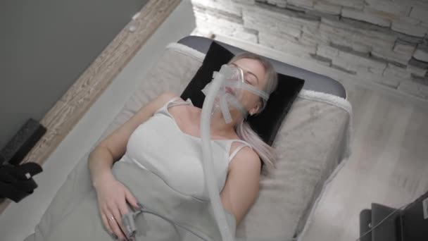 Girl lies on bed with artificial respiration mask — 图库视频影像