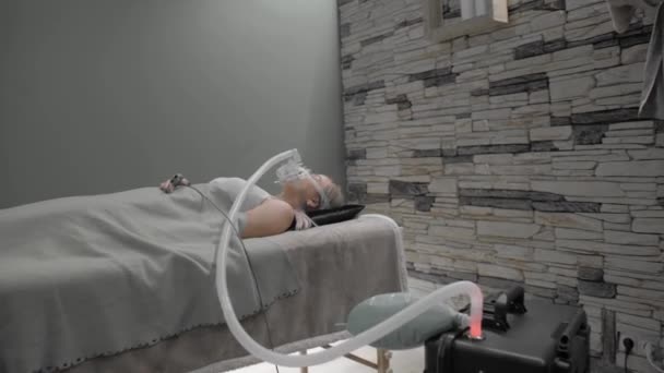 Chica se acuesta en la cama con máscara de respiración artificial — Vídeo de stock