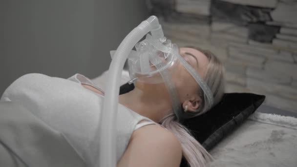 Girl lies on bed with artificial respiration mask — ストック動画