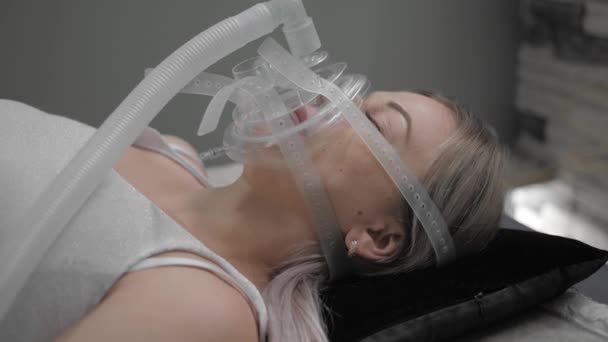 Girl lies on bed with artificial respiration mask — Stockvideo