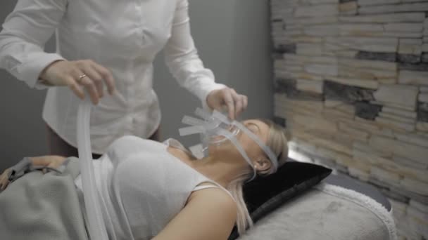 Girl lies on bed with artificial respiration mask — ストック動画