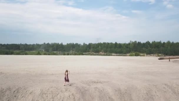 Meisje in een zonnejurk loopt langs de rand van een zandbak — Stockvideo