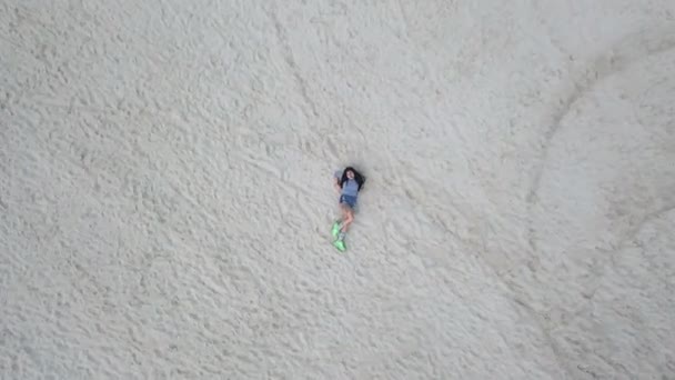 Chica se encuentra en la arena y mira hacia arriba — Vídeos de Stock