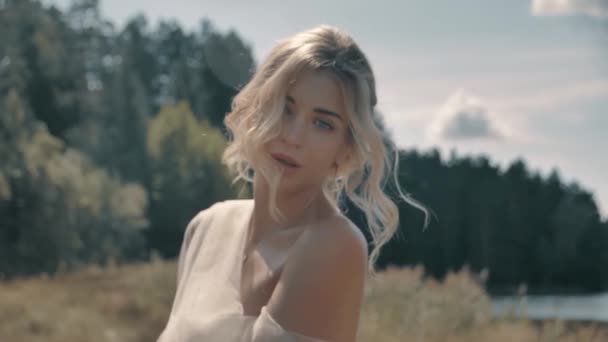 하얀 드레스를 입고 호수 근처에 앉아 있는 금발 소녀 — 비디오