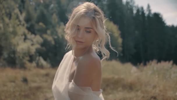 Chica rubia en un vestido blanco sentado cerca del lago — Vídeos de Stock