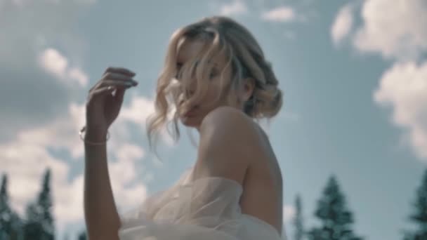 Blondes Mädchen in weißem Kleid sitzt in der Nähe des Sees aus nächster Nähe — Stockvideo