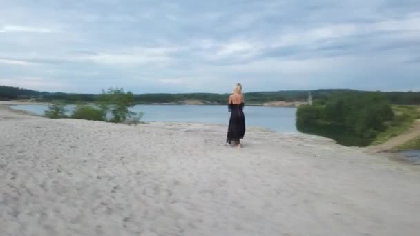Donna bionda con abito nero sulla spiaggia di sabbia — Video Stock