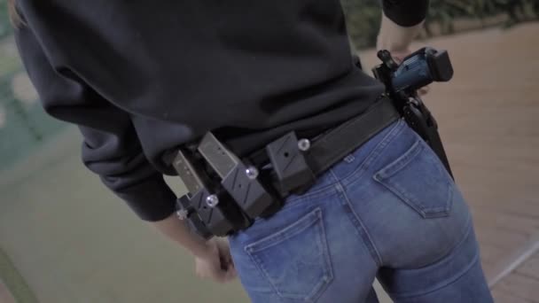 Cinturón de munición con pistola chica en ropa negra — Vídeos de Stock