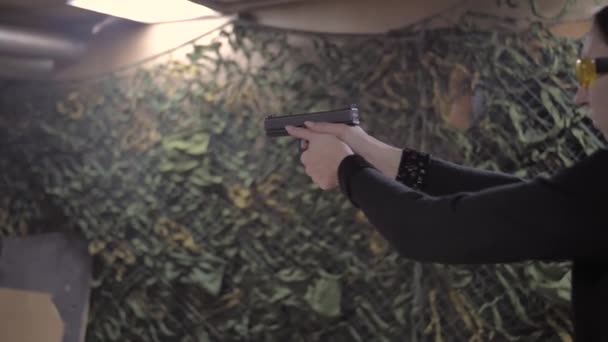 Mädchen in schwarzer Kleidung zieht Waffe aus Holster und schießt — Stockvideo