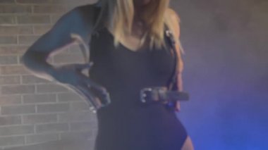 Siyah iç çamaşırlı, tuğladan duvarlı, renkli ışıklı güzel bir sarışın.