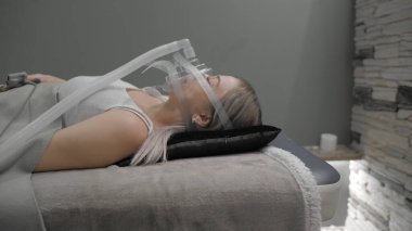Girl lies on bed with artificial respiration mask