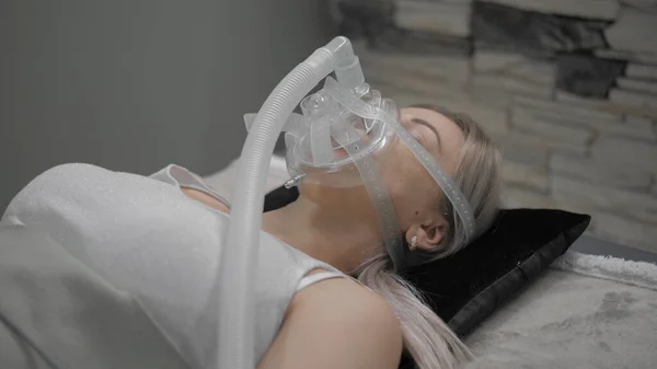 Дівчина лежить на ліжку зі штучною маскою дихання — стокове фото