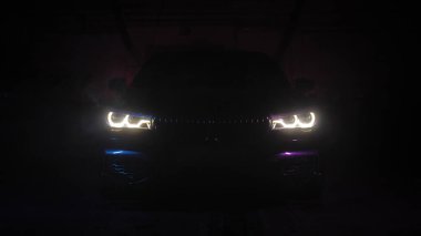 Şatafatlı siyah araba optiği duman ve siyah arka planda görünür. Renkli ışıklandırma