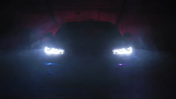 Роскошная черная оптика автомобиля сквозь дым, черный фон. Цветное освещение — стоковое фото