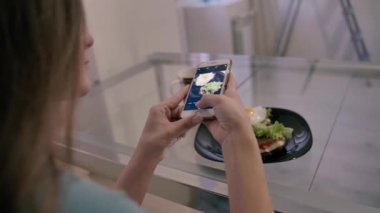 Instagram için güzel bir sandviçin fotoğrafını çeken bir kız.